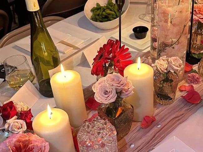Candlelit dinner table with red tapers and pink flowers