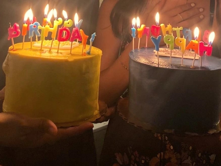 Two birthday cakes with lit letter candles