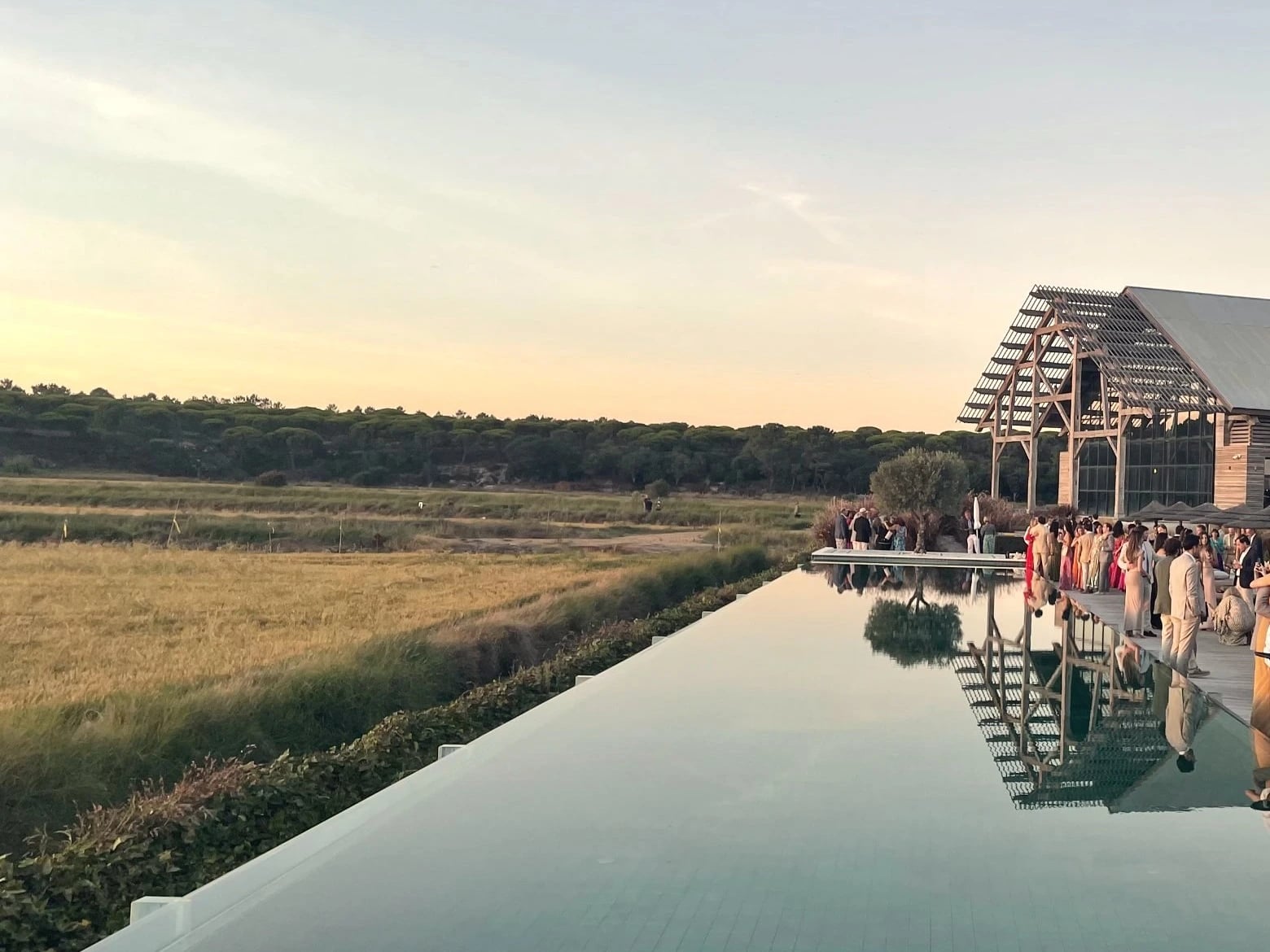 Friends gathered by a long reflecting pool at sunset