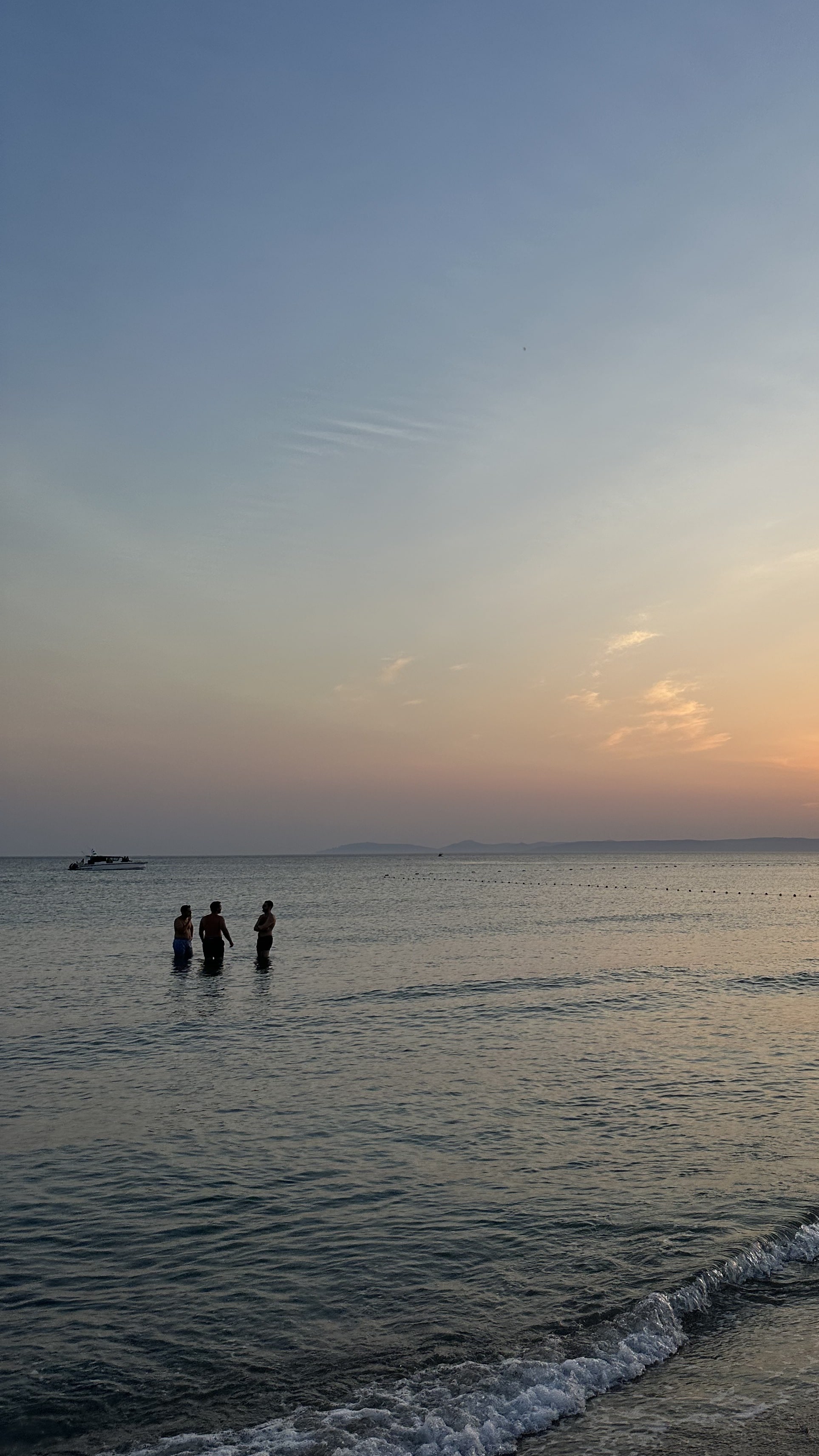 Three friends standing in the sea at sunset